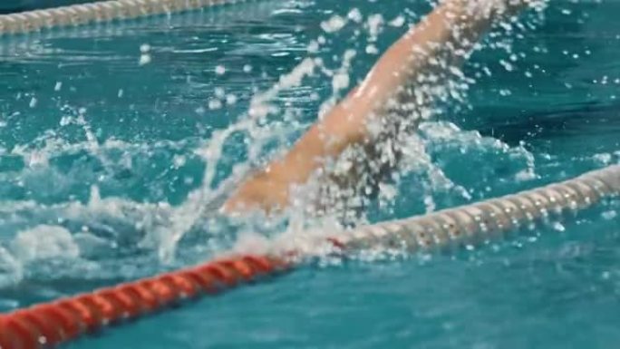 成功的男子游泳运动员在游泳池比赛。职业运动员决心使用前爬行自由泳赢得冠军。彩色电影镜头。后视图慢动作