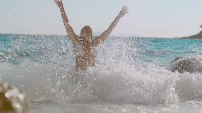 超级SLO MO女人在海浪从后面击中她时玩得很开心