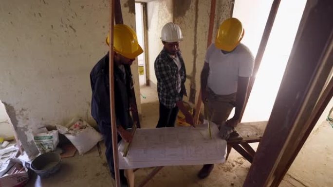 男性黑人建筑师在指向蓝图的同时向建筑工地的团队分配任务