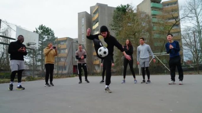 年轻的足球运动员与站在球场后面的朋友一起玩弄球
