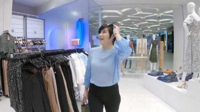优雅的亚洲中国女性在服装店散步购物