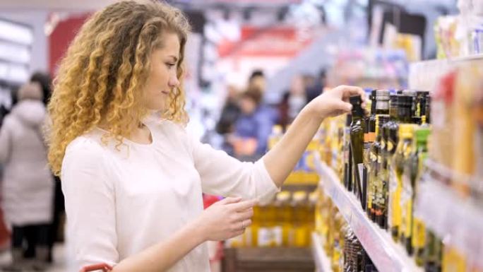 女人在杂货店买健康食品。年轻人在商店购物。一位30多岁的女性仔细分析市场上的产品。在超市选择并购买石