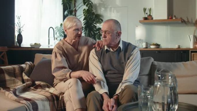 团结概念。70岁退休老人的肖像，夫妻微笑，坐在家里的沙发上聊天
