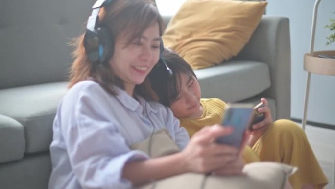 亚洲华裔妈妈享受周末闲暇与女儿用手机听音乐