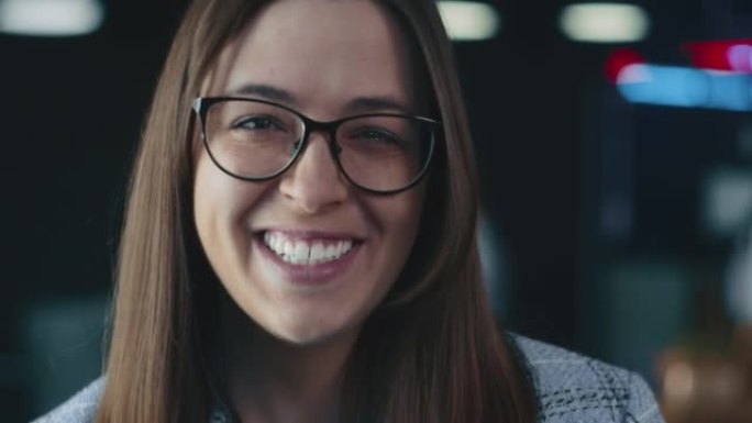快乐美丽的年轻高加索老板，戴眼镜的领导女商人在模糊的办公室背景下对着镜头微笑。