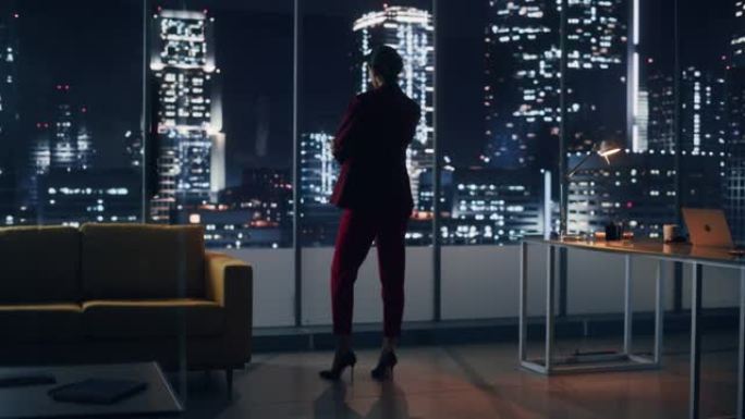 夜间办公室: 强大的女商人穿着时髦的西装站着，看着大城市的窗外。管理电子商务环境、社会和公司治理的女