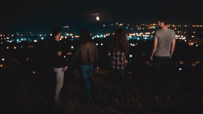 四人站在小山上夜城背景