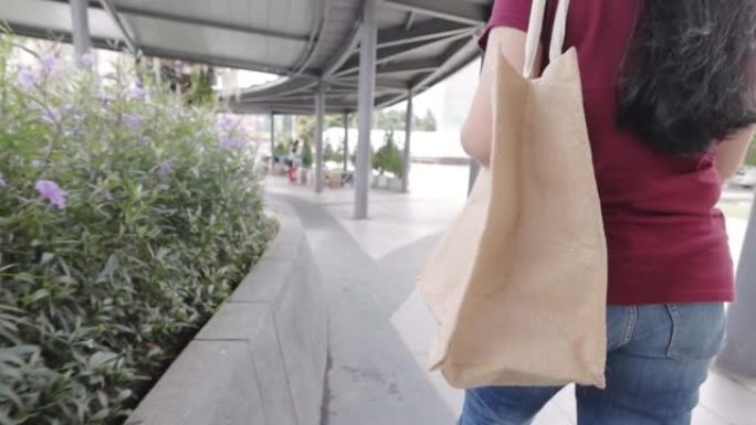 女人在购物中心里用可重复使用的袋子走路