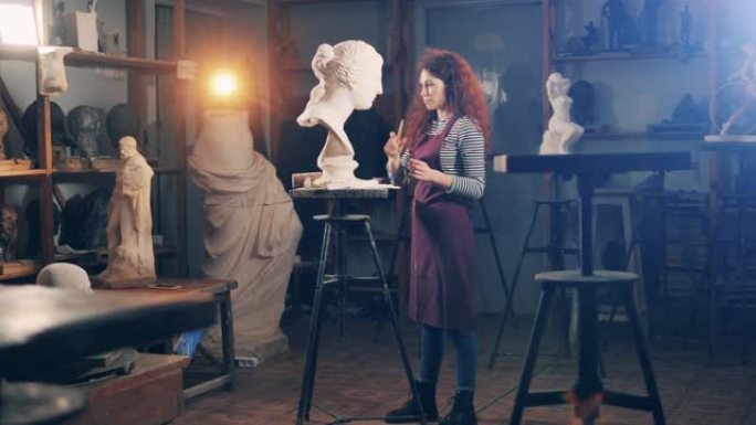 一位女士正在工作室里刷石膏半身像。灵感、创造力、设计、想象概念。