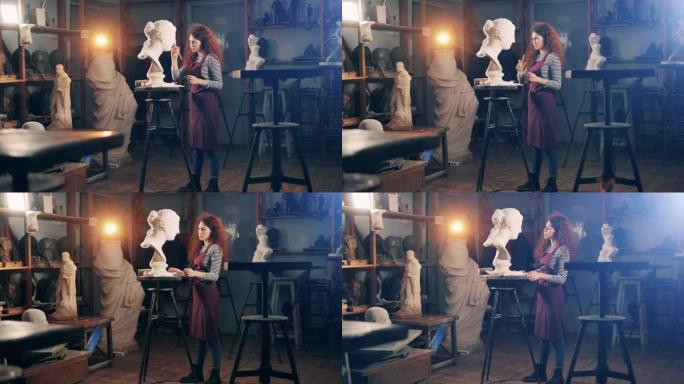 一位女士正在工作室里刷石膏半身像。灵感、创造力、设计、想象概念。