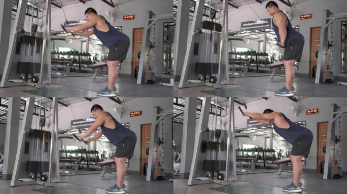 亚洲男子使用训练机锻炼背部肌肉在健身房锻炼
