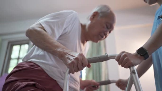 女亚洲医生帮助老年男性病人使用walker在家
