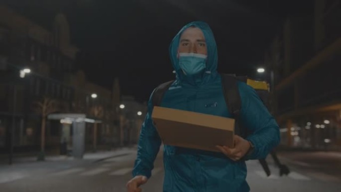 送餐员晚上在城市里用披萨盒跑步