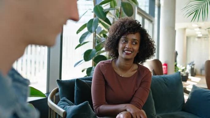 年轻的非洲妇女在办公室大厅与男同事交谈