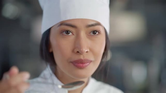 餐厅厨房: 亚洲女厨师准备菜肴，品尝食物并享受美食的肖像。专业烹饪美味、正宗、传统食品，使用健康食材