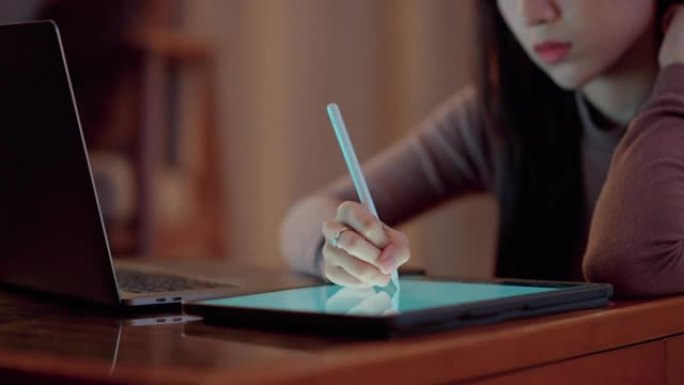亚洲设计师在家中使用数字平板电脑和数字化笔工作。