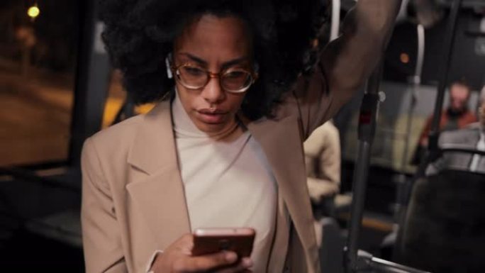 非裔美国女商人在公共巴士上通过智能手机发短信