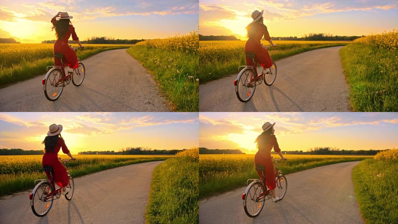 追踪一个无法辨认的黑发女性骑自行车进入日落的镜头，穿过一片充满活力的黄色金鱼草花朵，慢动作
