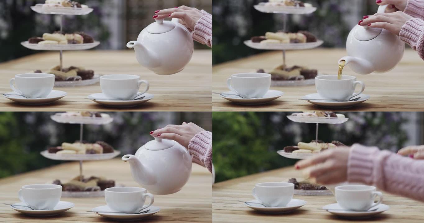 4k视频片段，一名妇女在外面的茶话会上将热茶倒入杯子中