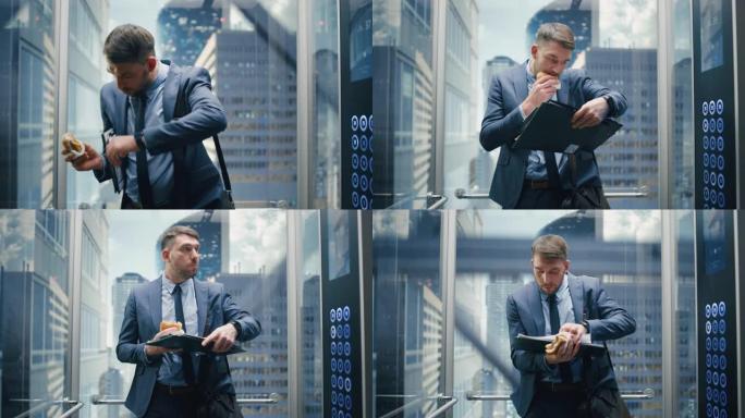 业务经理上班迟到，在现代办公楼里骑玻璃电梯。英俊的男人在乘电梯去公司会议的路上匆匆忙忙地吃了一个美味