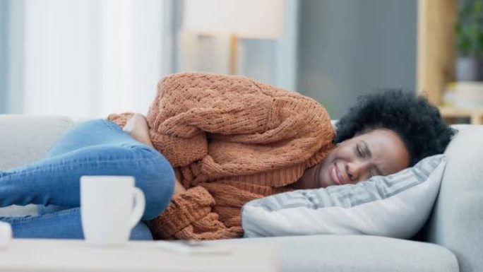 女人在家里的沙发上感觉不舒服，月经胃痉挛和肚痛。月经期间生病，肿胀和消化系统疼痛不舒服的女性