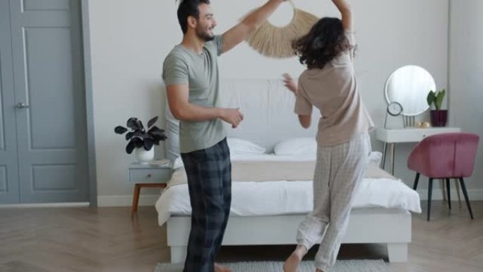 快乐的夫妻在卧室里跳舞，在家享受音乐和浪漫的时刻