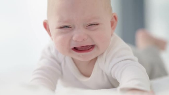 一个可爱的男婴在家里的床上哭泣的4k视频片段