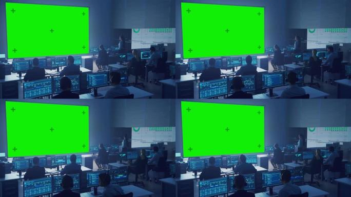 专业的计算机数据科学工程师团队在控制和监控室的台式机上工作。大显示屏有一个绿屏模型，其他显示图表、图