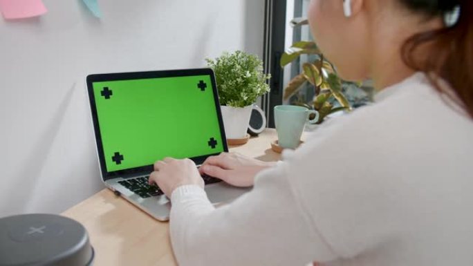 女人在家里的桌子上使用色度键屏幕笔记本电脑