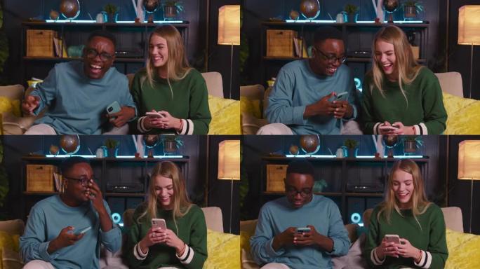 两个20多民族的快乐年轻朋友使用智能手机滚动互联网提要，在家里一起欢笑。
