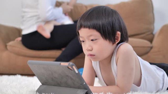 5岁的亚洲小男孩儿子在家学习在线课程，母亲在家母乳喂养婴儿。呆在家里预防冠状病毒或新型冠状病毒肺炎流