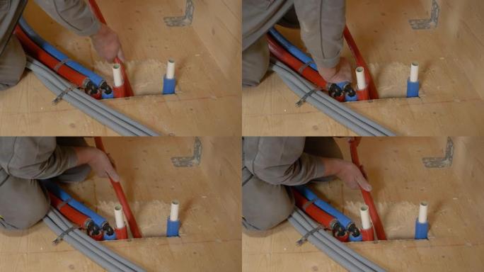 特写: 无法辨认的水管工将软管推入硬木地板的一个孔中。