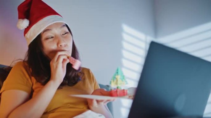 亚洲妇女使用笔记本电脑在晚上通过视频通话祝贺朋友或家人圣诞快乐