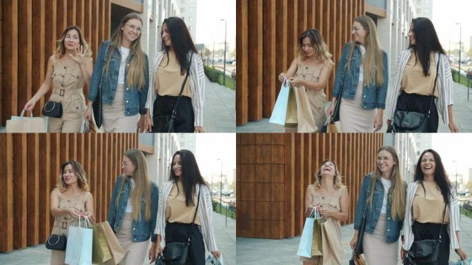 快乐的年轻女性朋友背着纸袋在户外散步，笑着说话