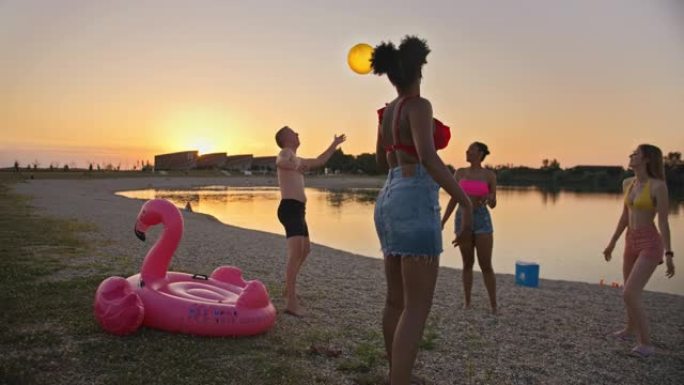 SLO MO一群年轻朋友在日落时在海滩上传球