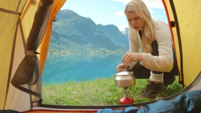 4k视频片段，一名迷人的年轻女子在Sogn og Fjordane露营时使用水壶