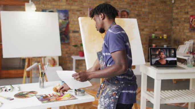 非裔美国男性画家在艺术家工作室拿着照片和混合颜料