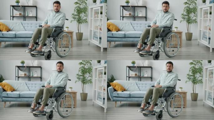 身体残疾男子的肖像坐在公寓的轮椅上看着相机
