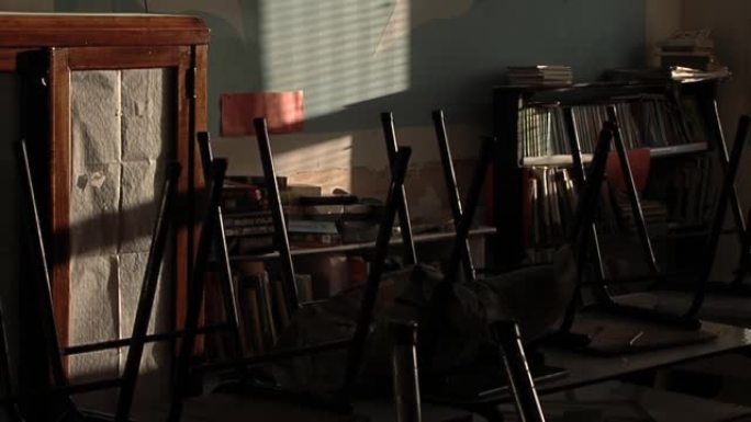 阿根廷一所关闭的学校的空教室里倒挂着老式胶合板和金属学校椅子。关闭了。
