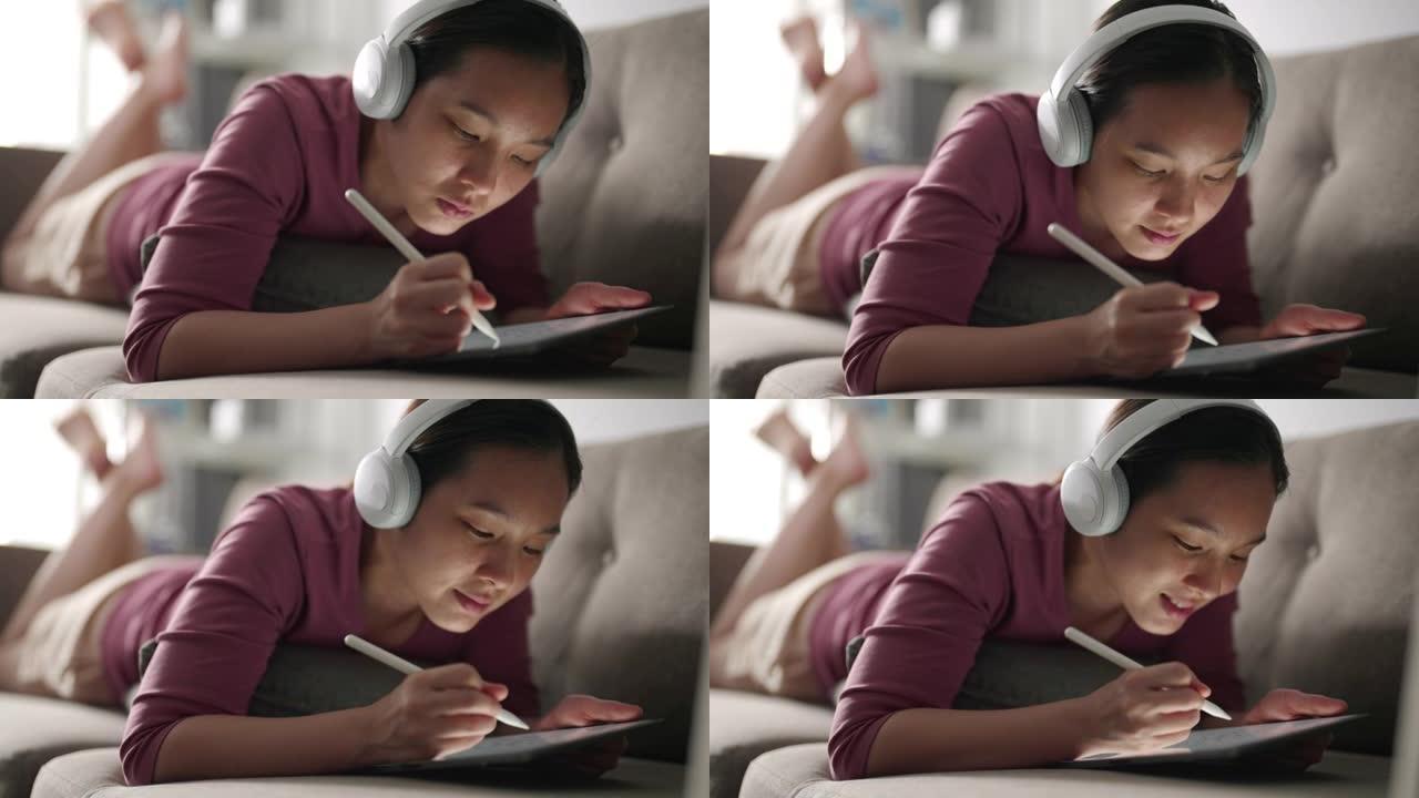 女人躺在沙发上，用耳机在平板电脑上写东西