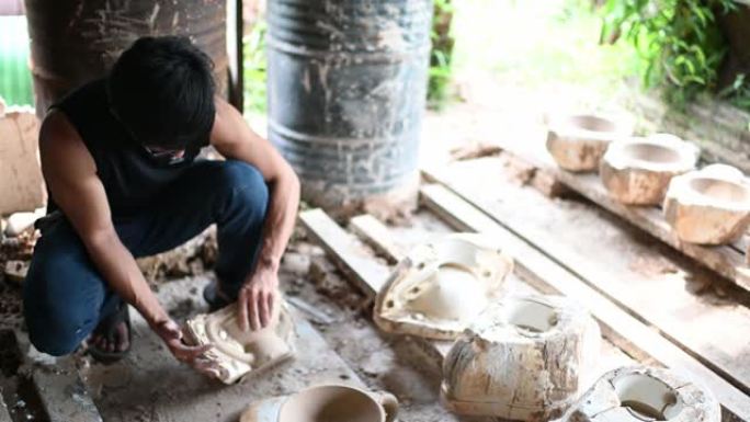 亚洲华人陶工破模烤箱后从模具中取回陶土花瓶