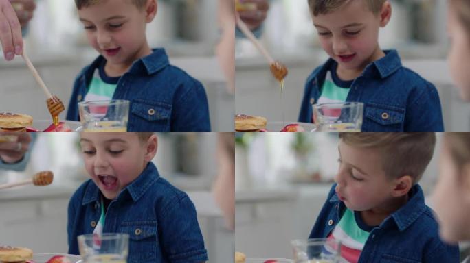 家庭吃早餐快乐的小男孩吃煎饼和姐姐一起倒美味的蜂蜜在周末早上在家准备自制餐4k镜头