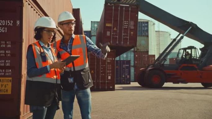 拥有平板电脑的多种族女性工业工程师和戴着安全帽和橙色高能见度背心的男工头站在集装箱码头。同事谈物流业