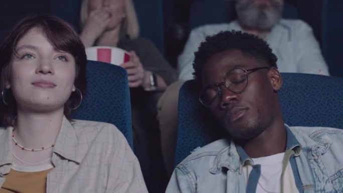 年轻女子和她昏昏欲睡的男友在电影院