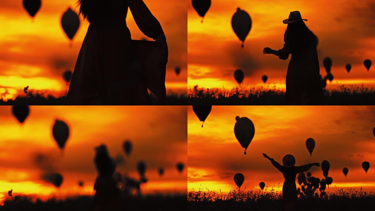 WS的剪影，一个无忧无虑的女人在日落时带着热气球在田野中行走