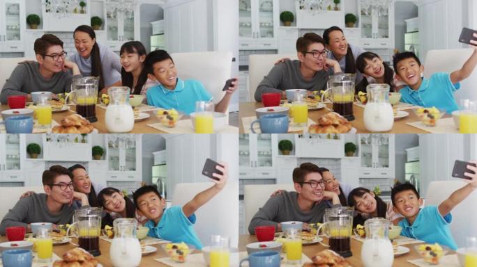 快乐的亚洲父母在厨房与儿子和女儿一起吃早餐，儿子集体自拍