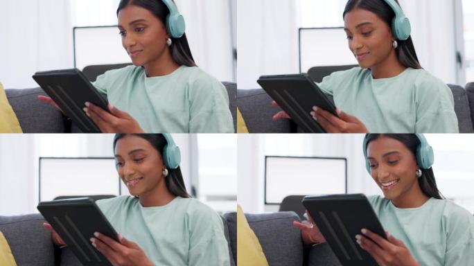女人在社交媒体或互联网上听音乐时戴着数字平板电脑和耳机。快乐的印度女孩社交网络与移动设备，同时在家里
