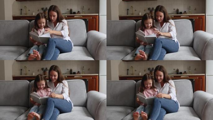 慈爱的妈妈看书她的小女儿坐在沙发上