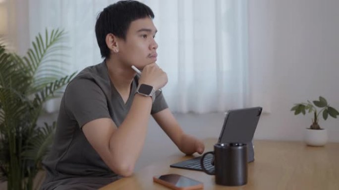 年轻的现代人坐在家里使用数字平板电脑工作。