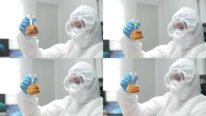 科学家戴着手套握住带有黄色液体的无菌烧瓶